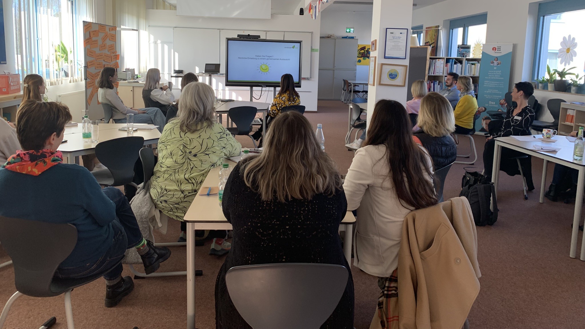 Zu sehen sind die Teilnehmenden des Fachaustausches. Diese sitzen an Gruppentischen und schauen zur Präsentation.